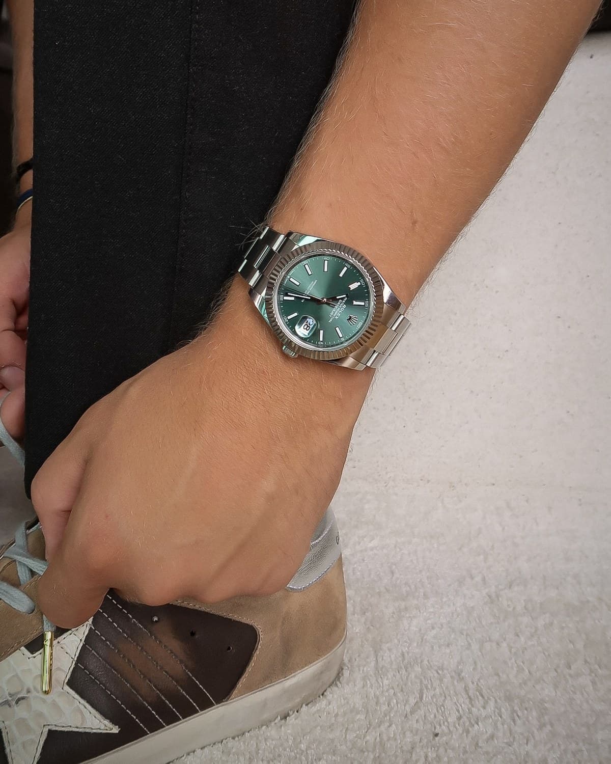 A green-dial watch on the wrist