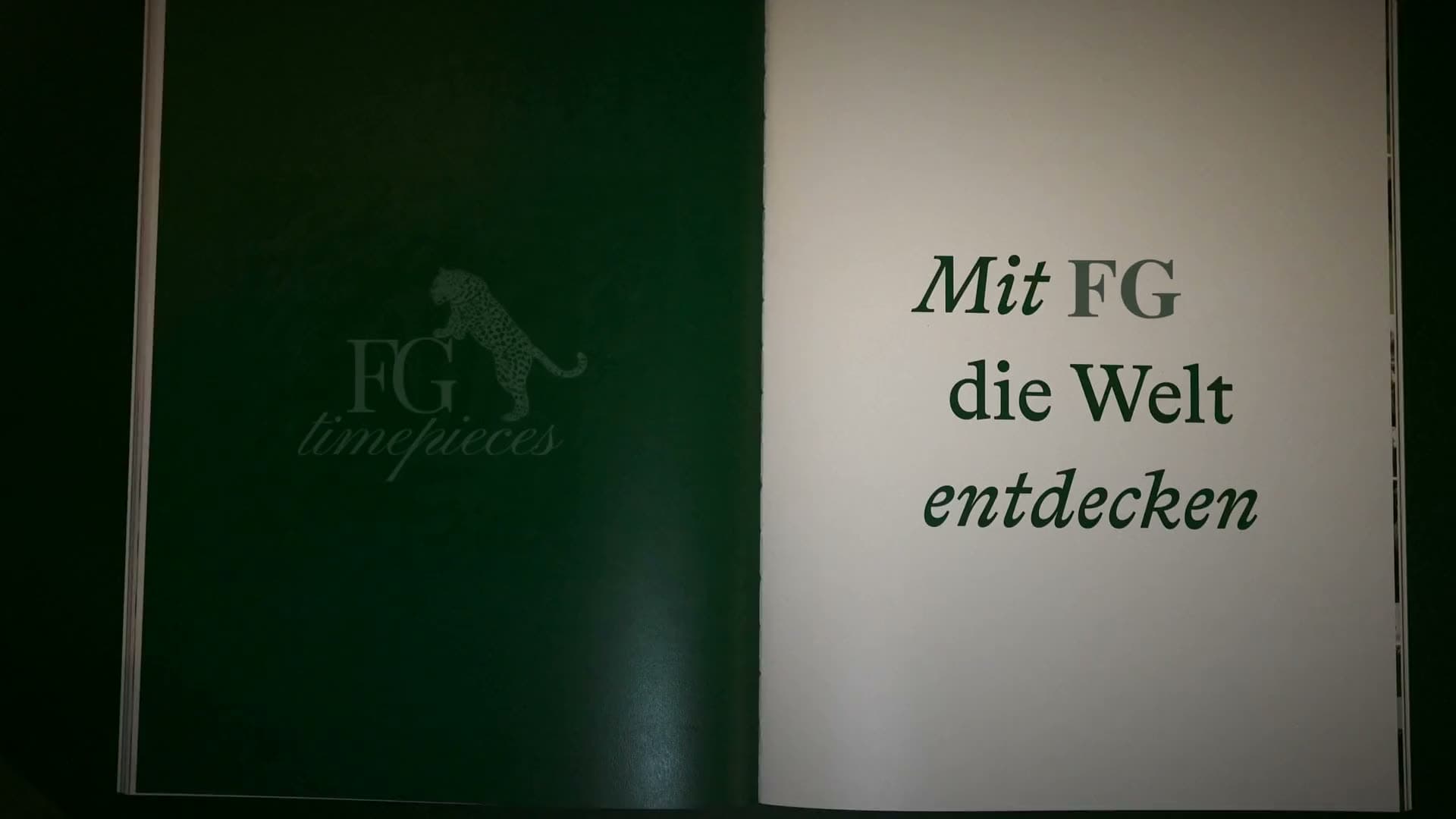 A watch resting on an open book, in the FG timepieces green box
